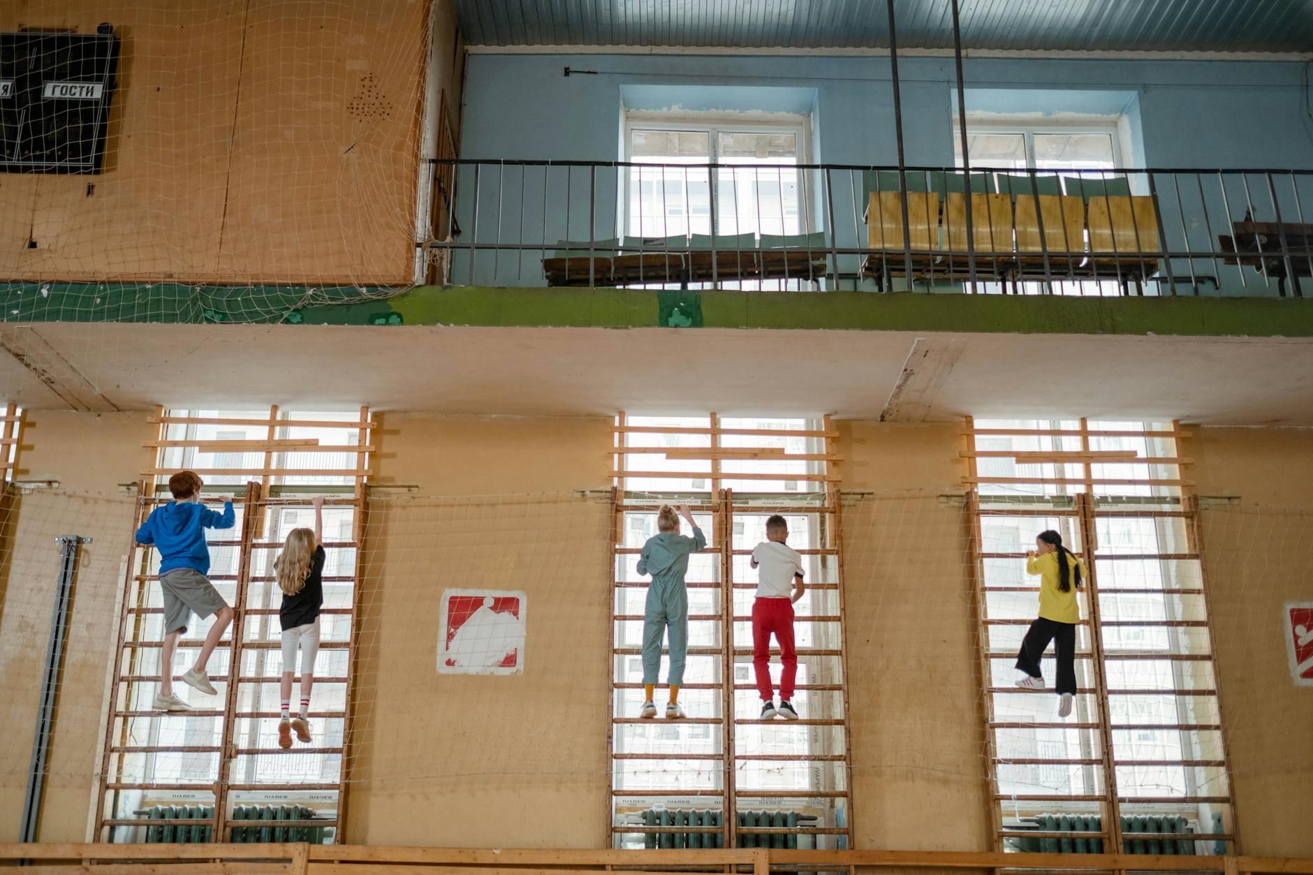 Dzieci wspinające się na ściance w małej hali sportowej