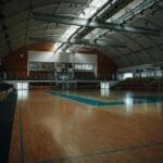 Pusta hala sportowa z parkietem i składanymi trybunami