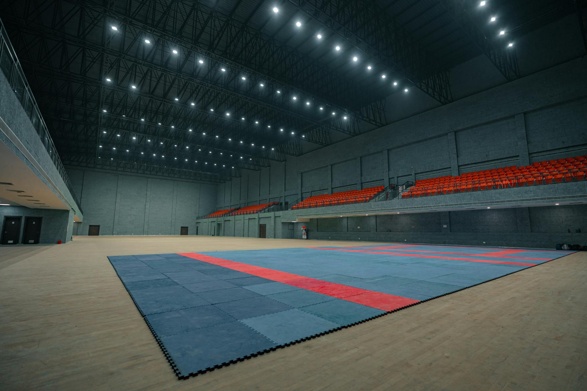 Duża hala sportowa z matą i trybunami, widok z wyższej kondygnacji
