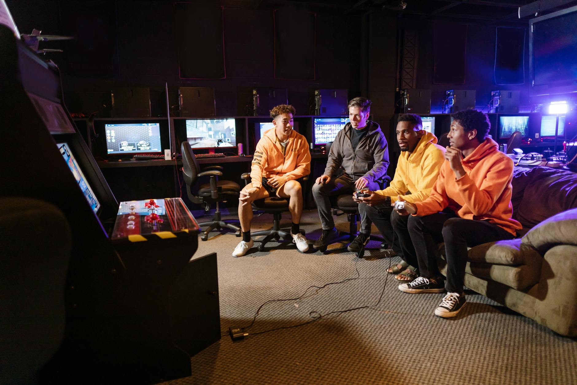 Grupa młodych mężczyzn grających razem na automatach i padach