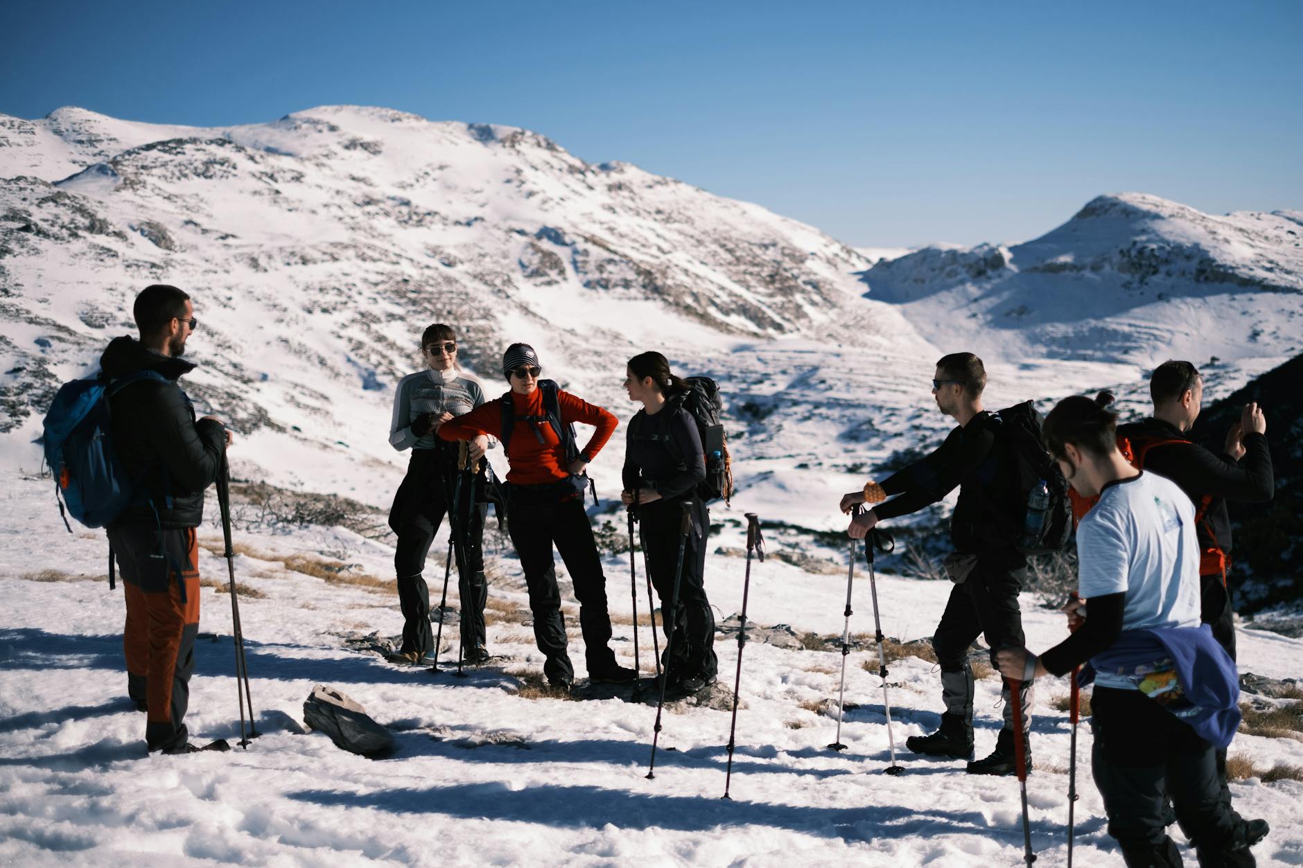 Grupa turystów z kijkami trekkingowymi idzie po ośnieżonych górach