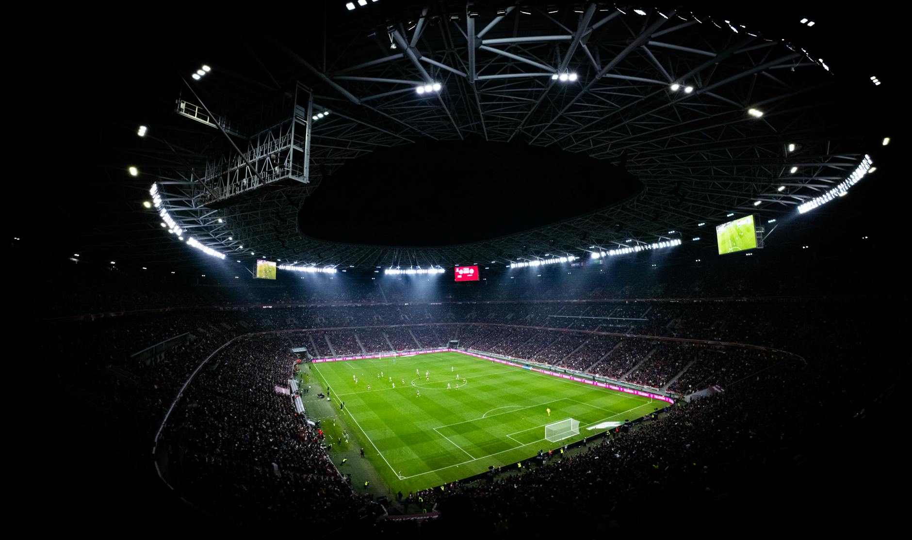 Nocny mecz piłkarski w wypełnionym kibicami stadionie w Budapeszcie