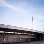 Najciekawsze rozwiązania wejść i bramek na nowoczesnych stadionach Nowoczesna fasada stadionu piłkarskiego na tle błękitnego nieba