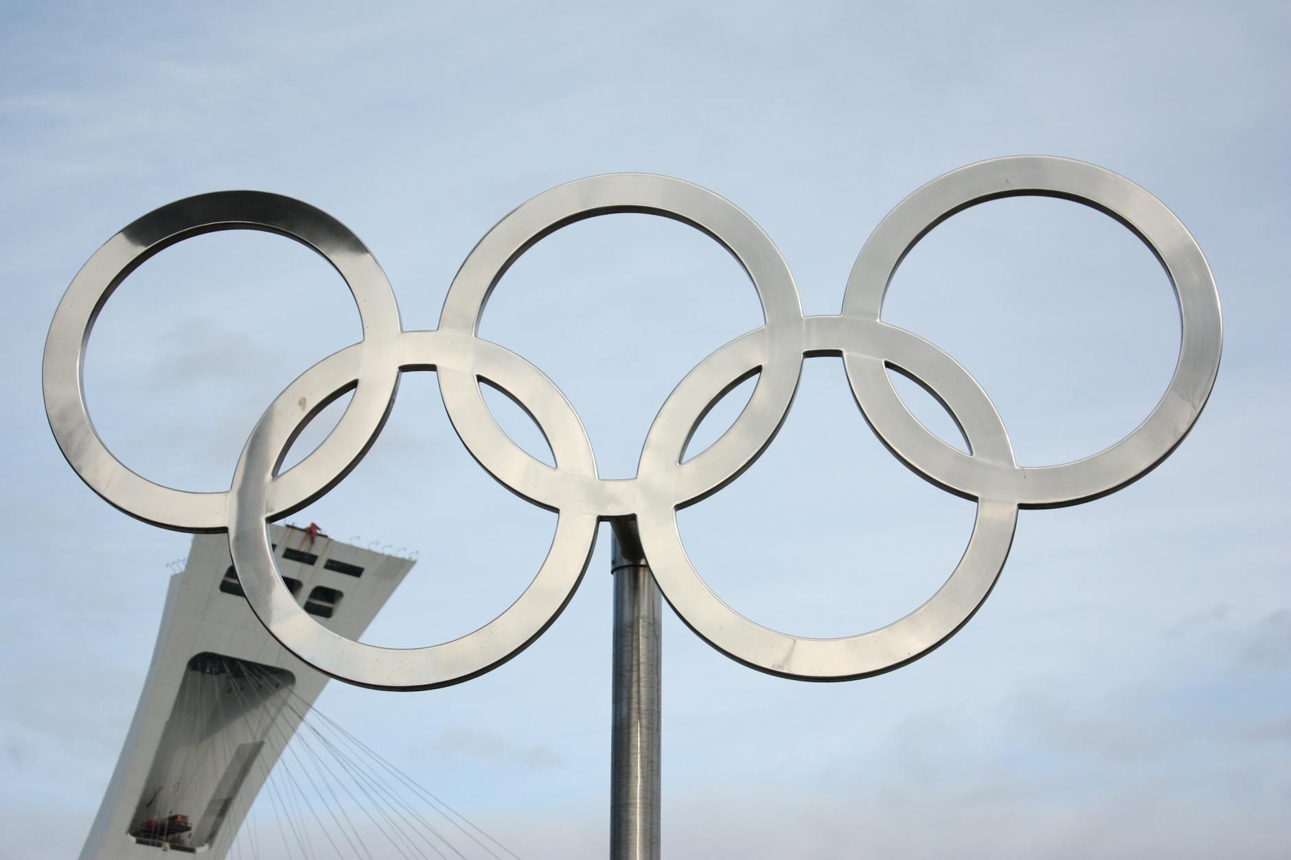 Kolorowe koła olimpijskie przed wysokim budynkiem w słoneczny dzień