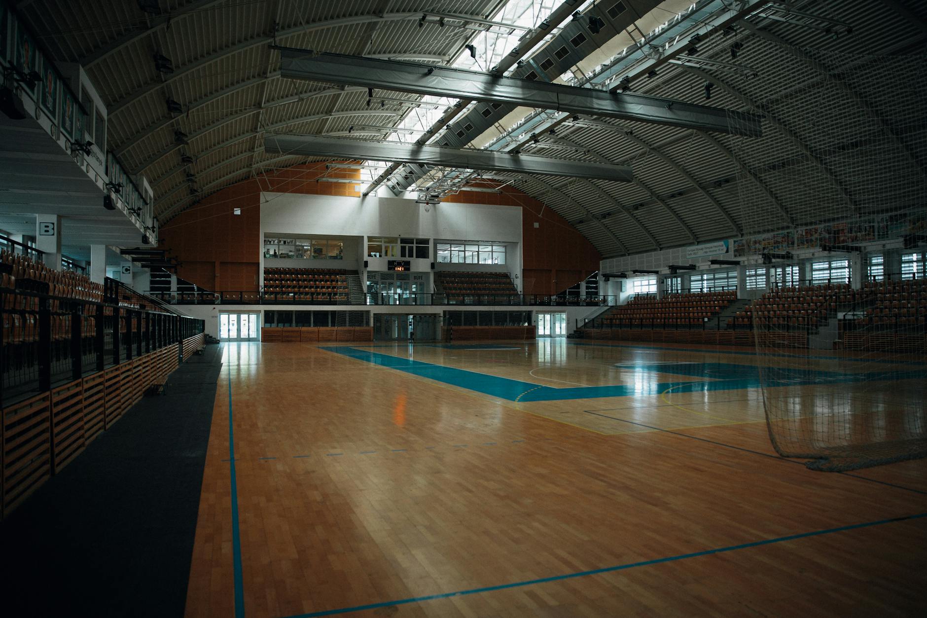 Pusta hala sportowa z parkietem i składanymi trybunami