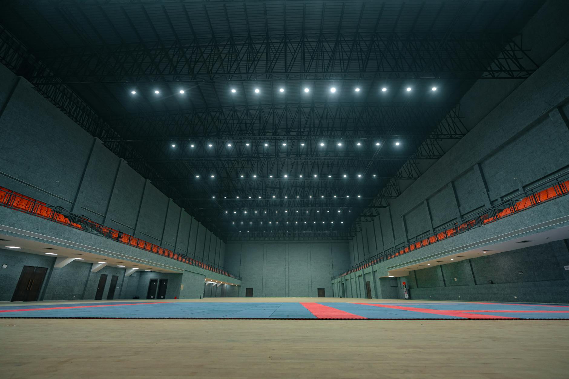 Pusta, jasno oświetlona hala sportowa z widocznym sufitem i parkietem