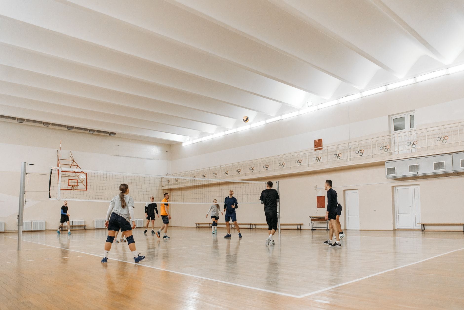 Siatkarze grający mecz w nowoczesnej hali sportowej z parkietem