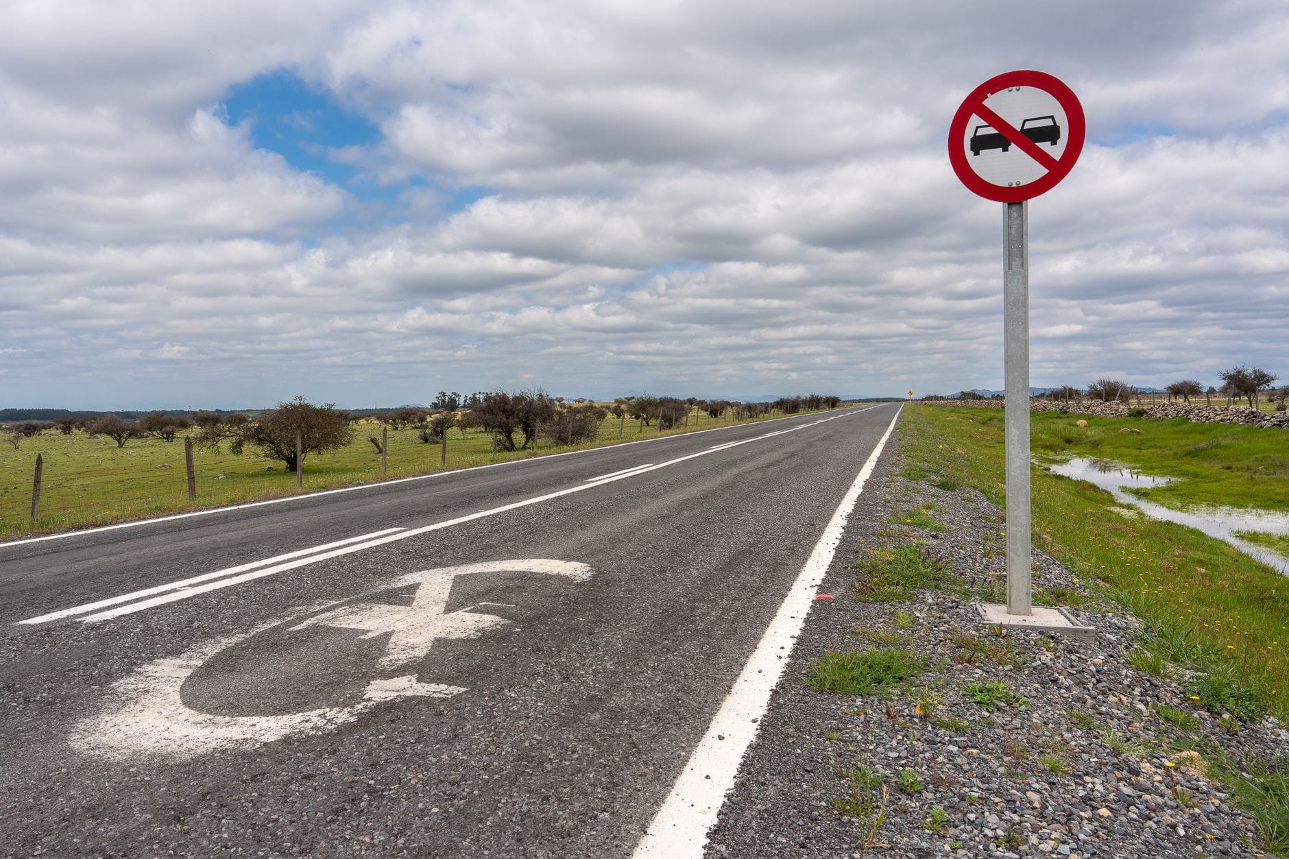 Jak bezpiecznie wyprzedzać na drogach ekspresowych i autostradach: zasady, przepisy i najczęstsze błędy kierowców Znak zakazu wyprzedzania przy pustej wiejskiej drodze pod chmurami