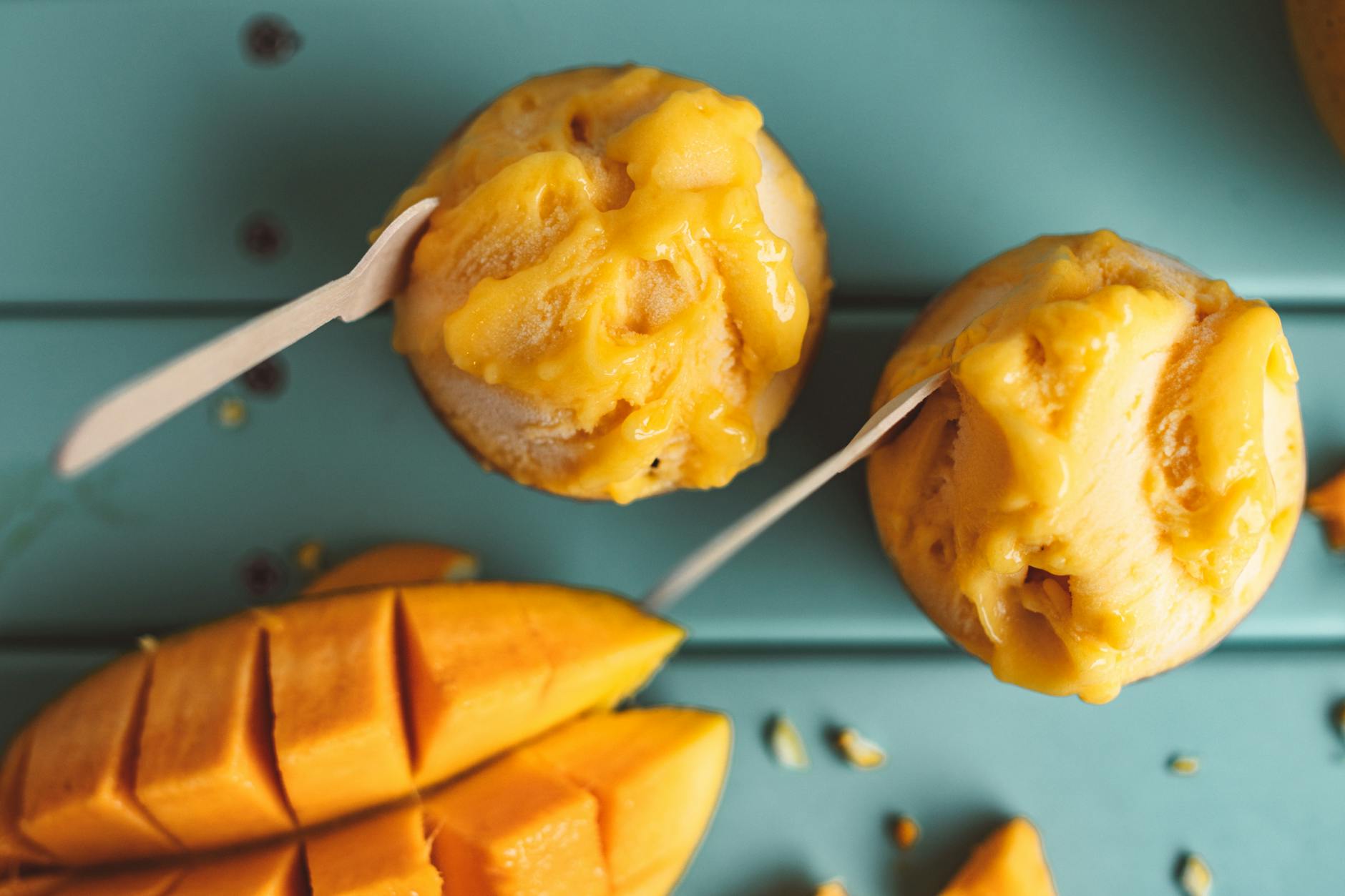 Domowy sorbet mango z plasterkami mango na turkusowym tle