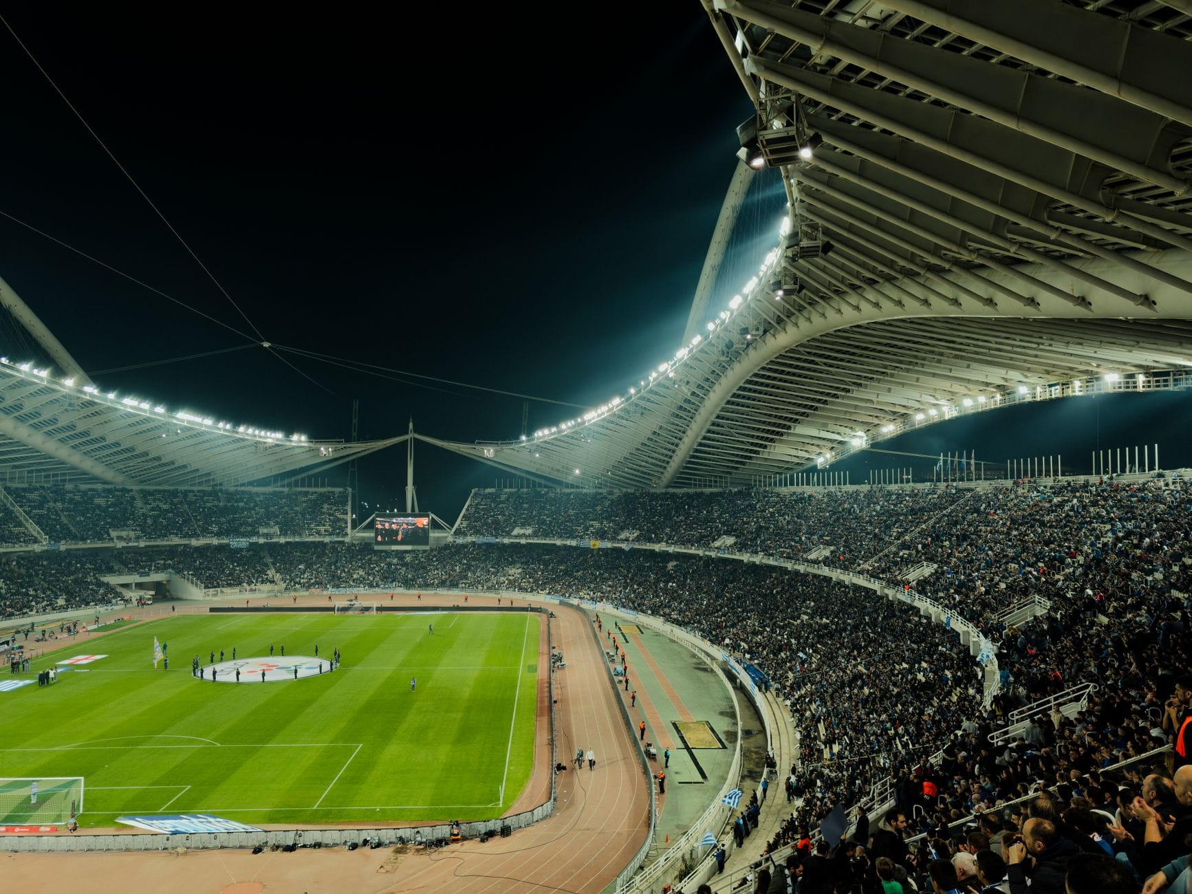 Największe stadiony w Polsce: ranking pojemności Pełne trybuny piłkarskiego stadionu nocą w blasku jupiterów