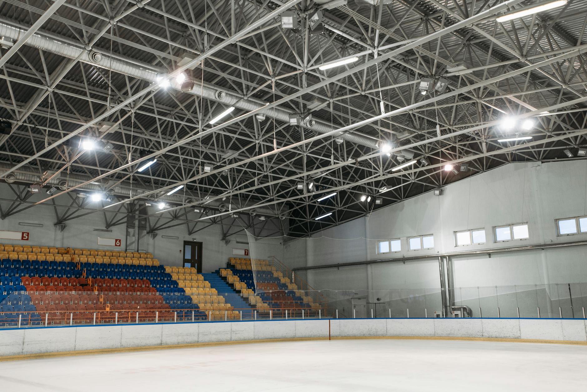 Pusta hala sportowa z lodowiskiem i kolorowymi trybunami