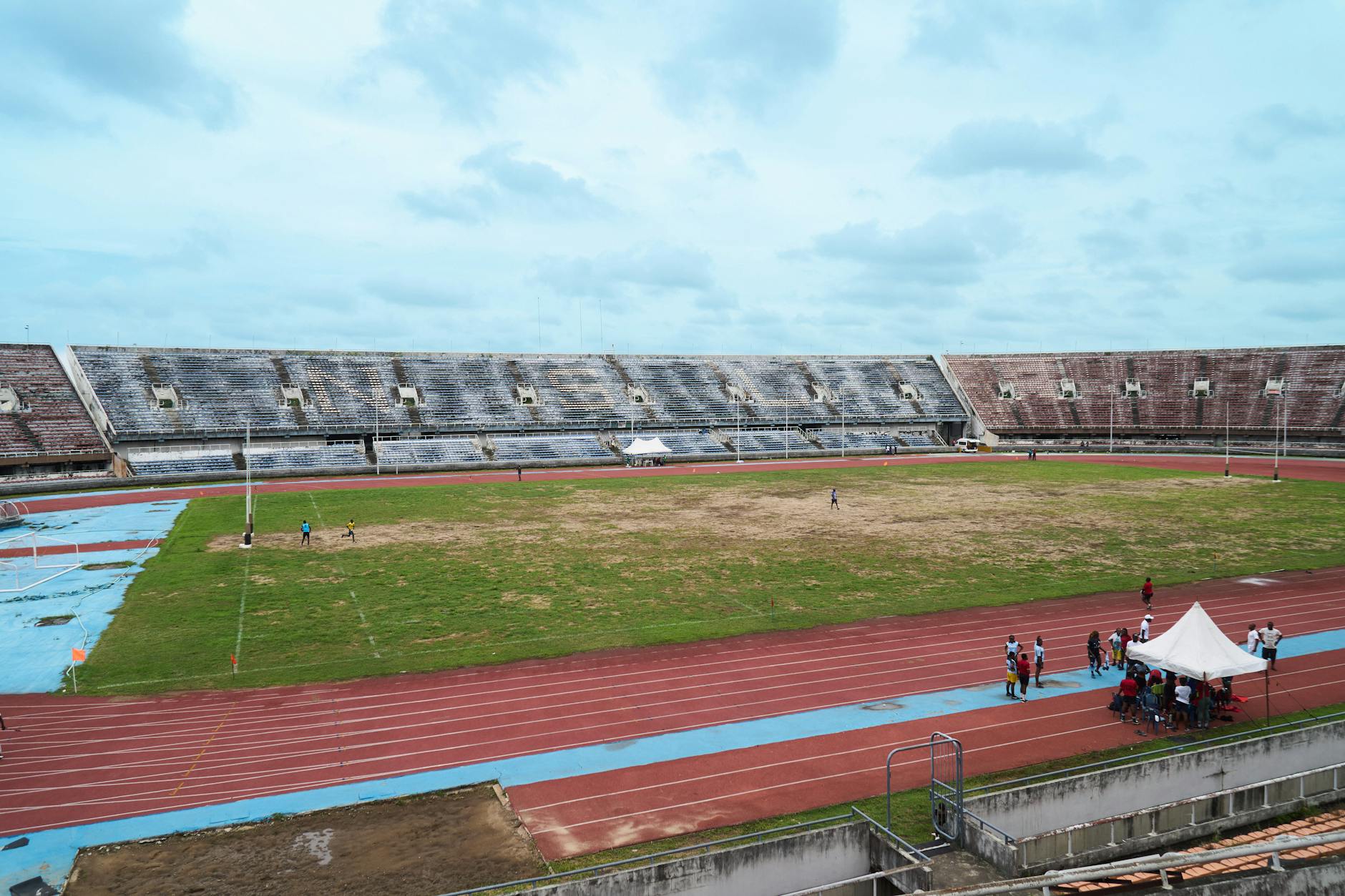 Puste lekkoatletyczne boisko ze stadionową bieżnią pod zachmurzonym niebem