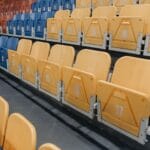 Jak mierzy się widoczność z miejsc w hali i dlaczego niektóre sektory są pechowe? Kolorowe puste krzesełka na trybunach hali sportowej
