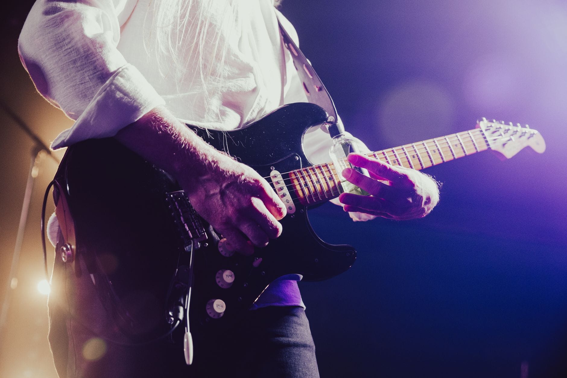 Gitarzysta rockowy grający z pasją na scenie w kolorowych światłach Gitarzysta rockowy grający z pasją na scenie w kolorowych światłach