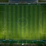 Stadiony z muzeum na miejscu: gdzie historia klubu jest częścią zwiedzania Widok z lotu ptaka na boisko piłkarskie z zawodnikami w trakcie meczu