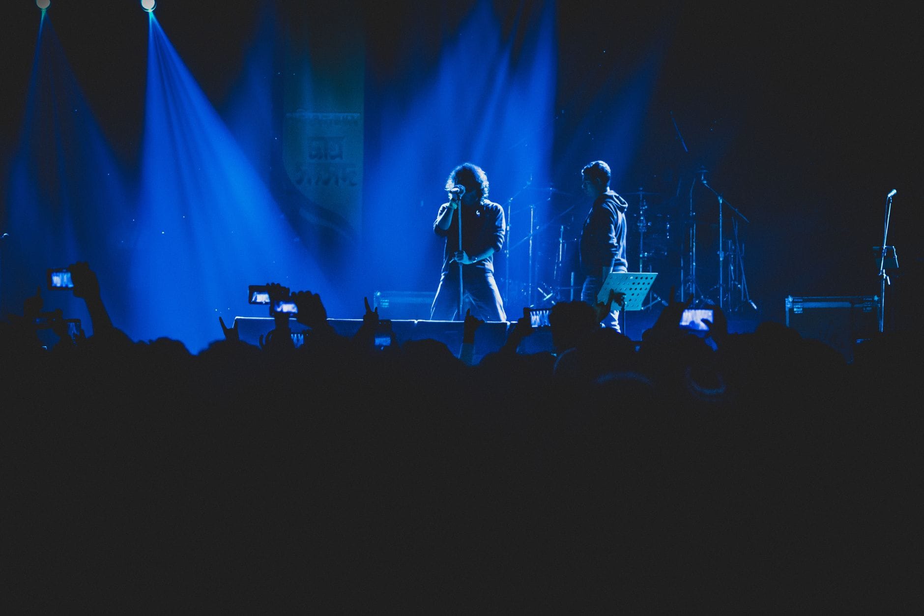 Wokalista i zespół rockowy na scenie w kolorowych światłach koncertu